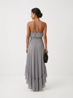 Elegante vestido de invitada de boda gris con cuello halter y bajo asimétrico de volantes