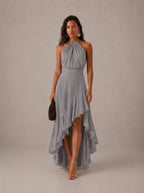 Elegante vestido de invitada de boda gris con cuello halter y bajo asimétrico de volantes