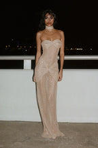 Refinado vestido largo beige palabra de honor de invitada de boda con acabado brillante y plisado | Maxi