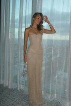 Refinado vestido largo beige palabra de honor de invitada de boda con acabado brillante y plisado | Maxi